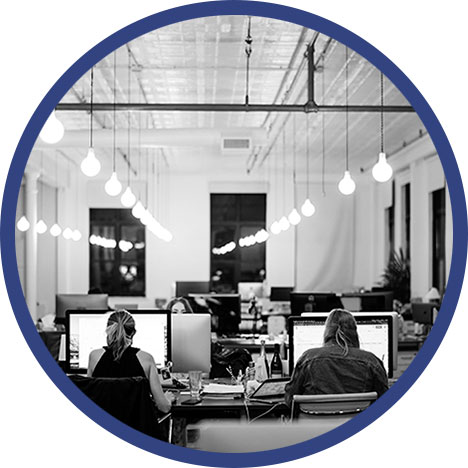 Frauen, die in einem Großraum-Büro sitzen und an Computern arbeiten.