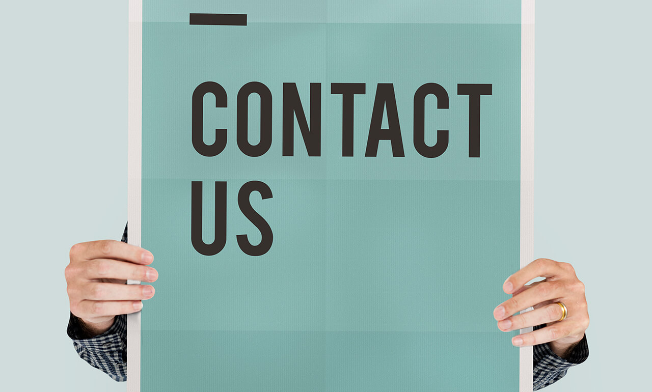 Eine Person, die ein Plakat hochhält, auf dem CONTACT US steht.