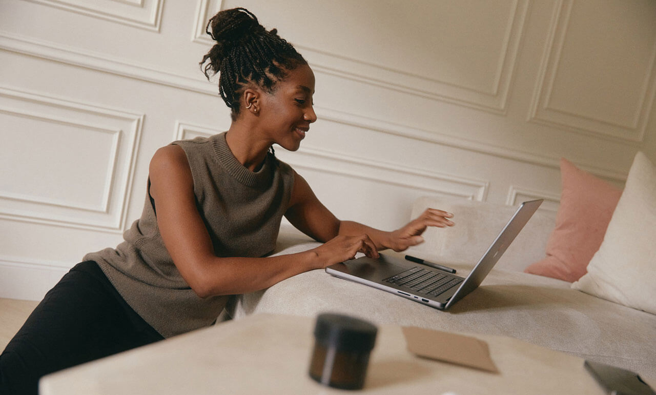Eine Frau, die an einem Notebook arbeitet, der auf einem Bett steht.