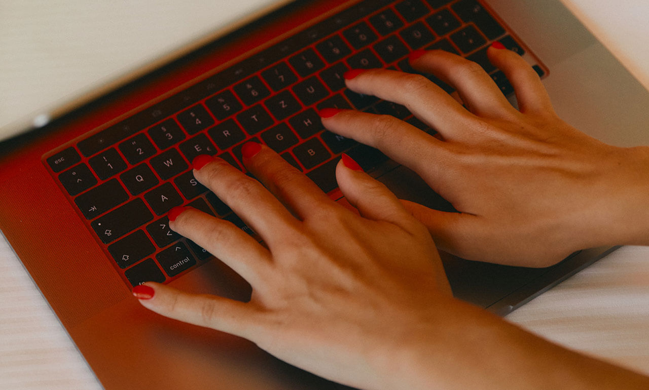 Zwei Hände, die auf einer Tastatur eines Notebooks schreiben.